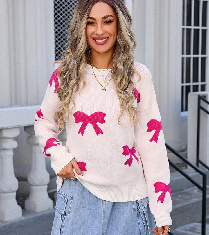 Smiling woman wearing cream sweater with pink bow patterns and light blue cargo jeans outdoors