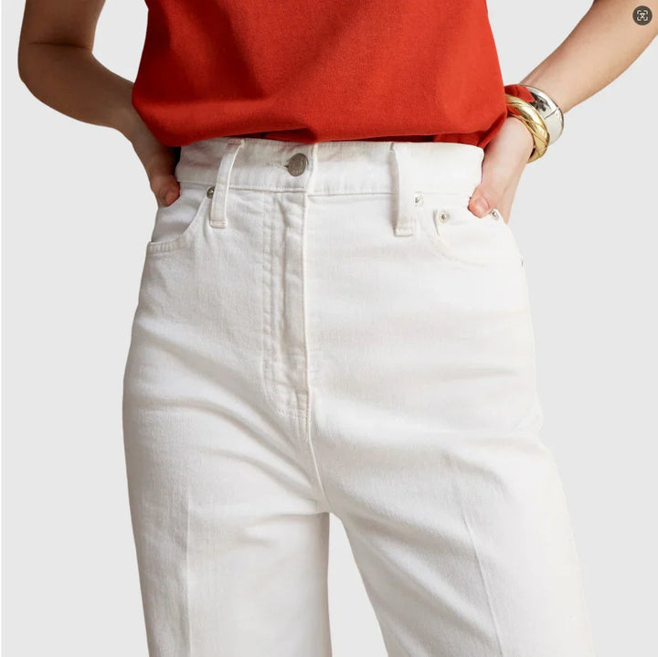 Woman wearing high-waisted white denim jeans and a red top with gold and silver bangles