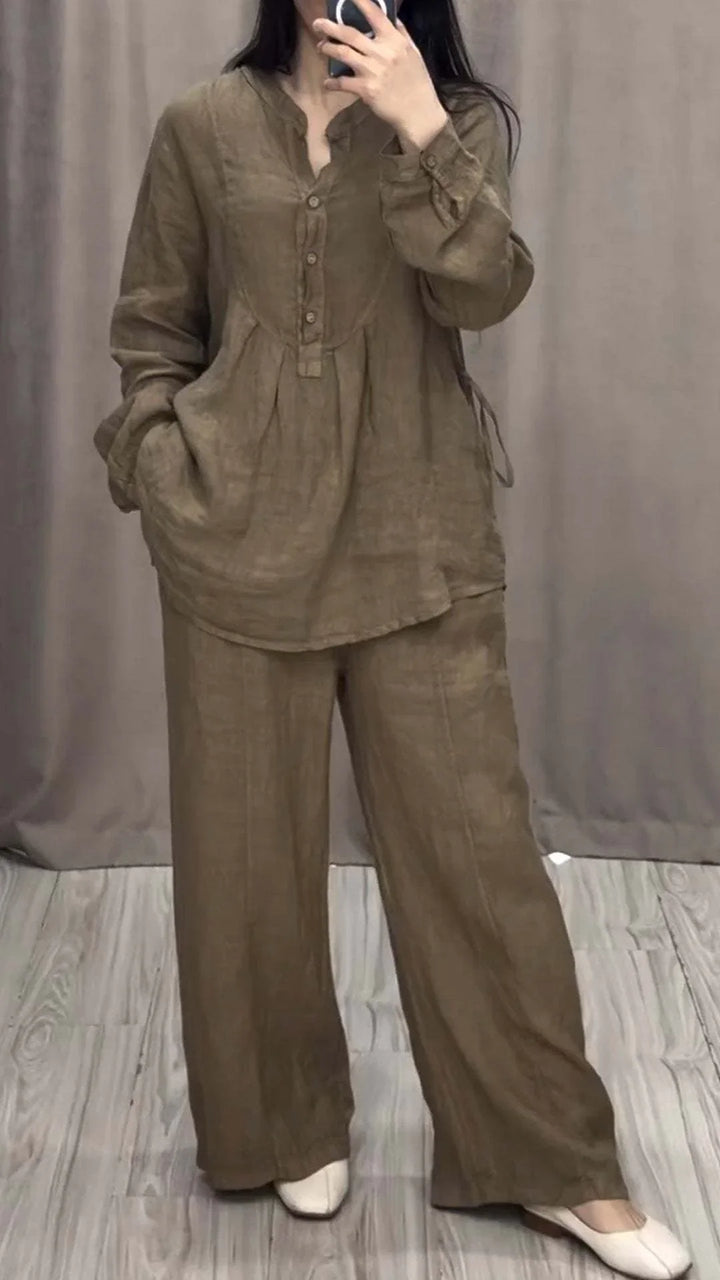 Woman wearing loose brown linen tunic and wide-leg pants outfit with white shoes in neutral room