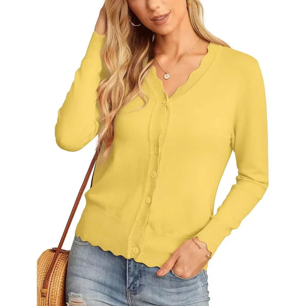Woman wearing yellow scalloped edge button-up cardigan with light blue distressed jeans and a wicker shoulder bag