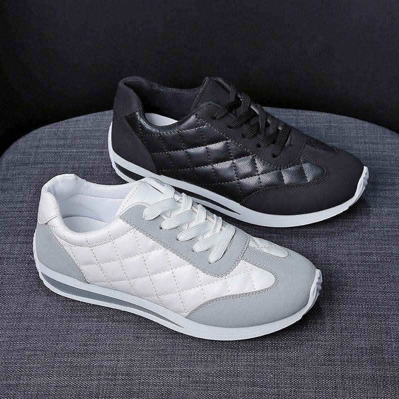 Pair of quilted leather sneakers in black and white with gray suede accents on gray fabric surface