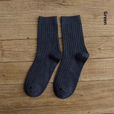 Pair of dark green ribbed socks laid flat on wooden surface, labeled Green
