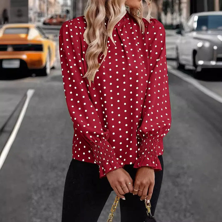 Woman wearing red polka dot blouse with smocked cuffs holding chain handbag on city street