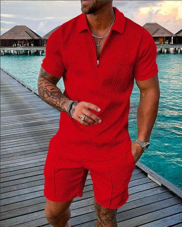 Man wearing stylish red short-sleeve polo and matching shorts on wooden pier by turquoise water villas