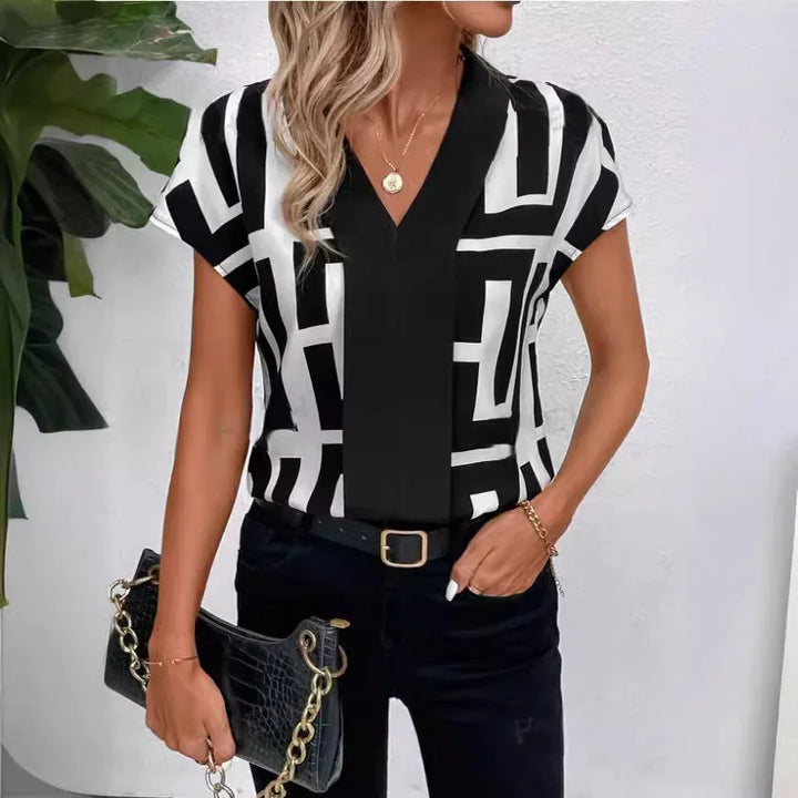 Woman wearing black and white geometric print blouse with black pants and gold accessories