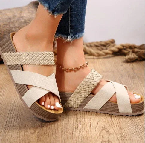 Beige platform sandals with braided straps worn with blue frayed hem jeans on wooden floor