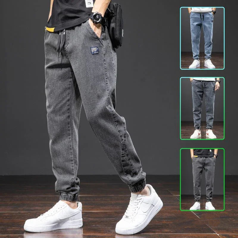 Men's casual jogger pants in black, blue, and gray denim styles with elastic cuffs and white sneakers