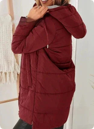 Woman wearing a warm maroon hooded quilted jacket indoors