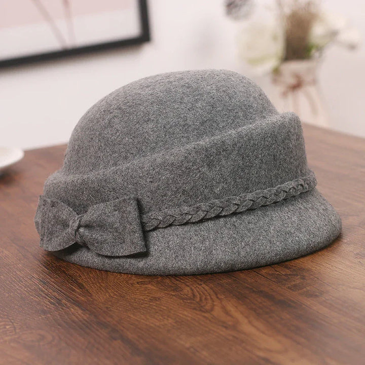 Grey wool cloche hat with braided band and bow detail on wooden table
