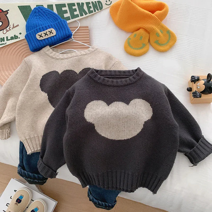 Two kids' sweaters with teddy bear silhouettes, paired with jeans, a blue beanie and yellow mittens