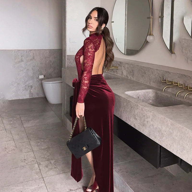 Woman in burgundy velvet and lace backless dress holding black Chanel handbag in modern bathroom