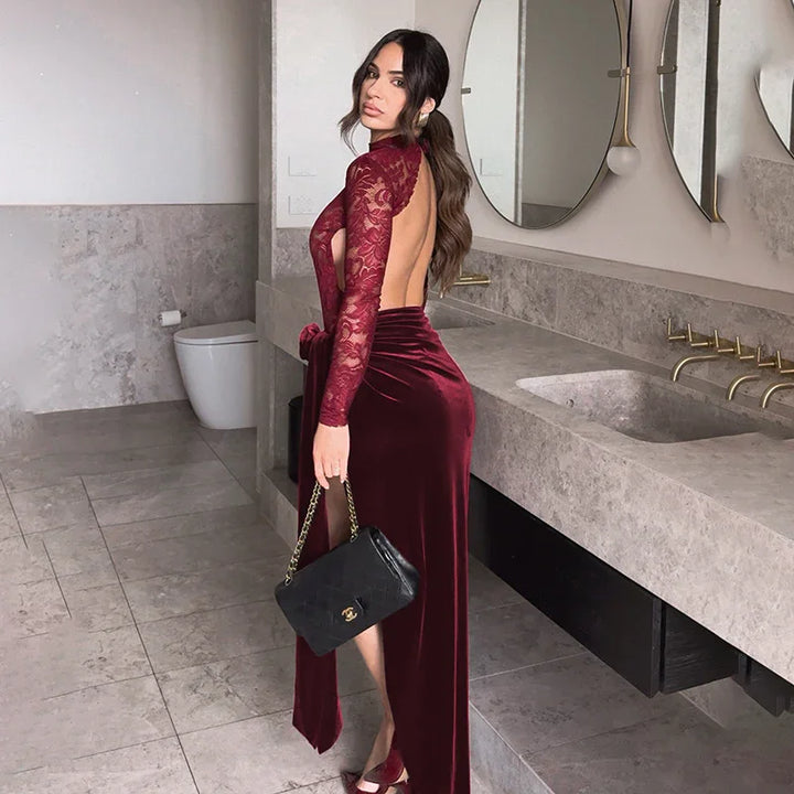 Woman in burgundy velvet and lace backless dress holding black Chanel handbag in modern bathroom
