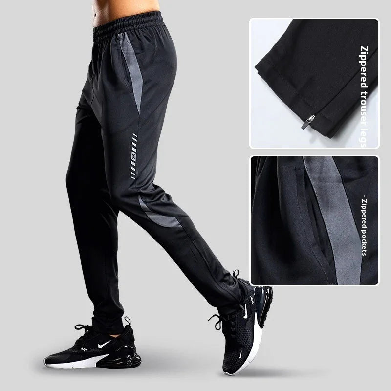 Men's black athletic track pants with gray accents, zippered pockets, and zippered trouser legs