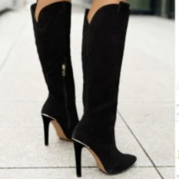 Black high-heeled knee-high boots with pointed toes worn outdoors on tiled pavement