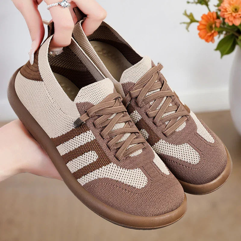 Light brown and beige knitted casual sneakers with brown soles held by hand indoors