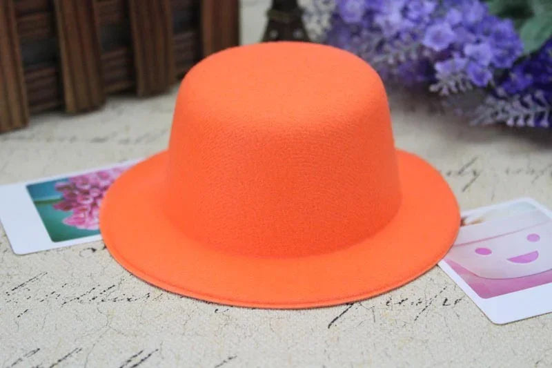 Bright orange wool felt bowler hat on textured surface with flower photos and purple flowers backdrop