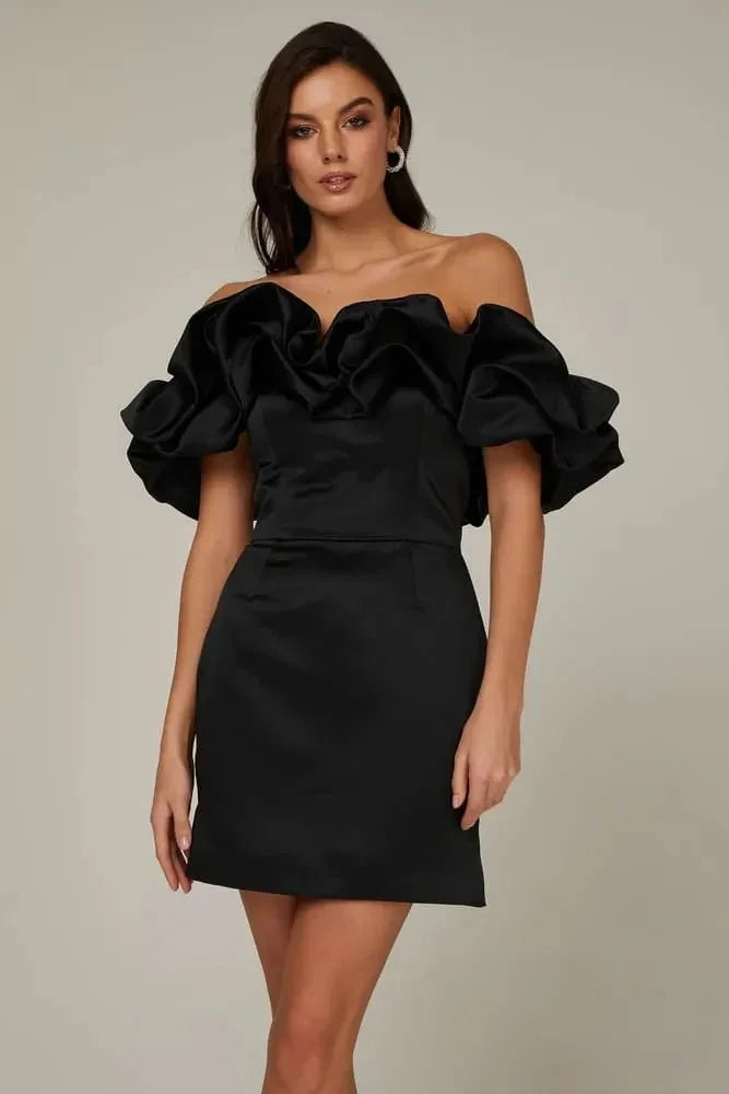 Woman wearing elegant black off-shoulder mini dress with voluminous ruffled sleeves