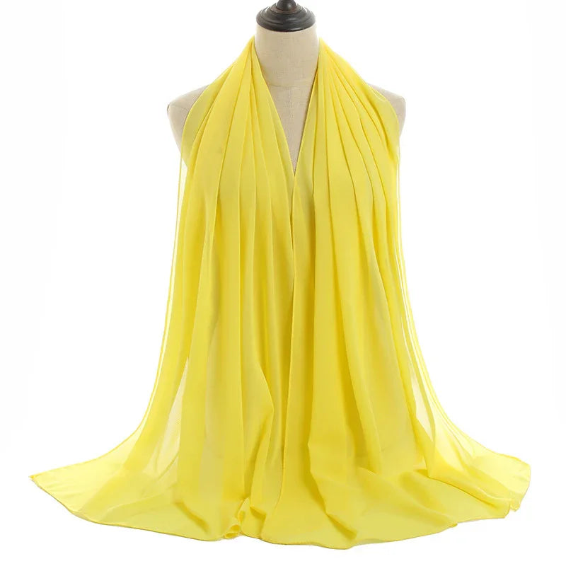 Lightweight yellow chiffon scarf draped on a mannequin against white background