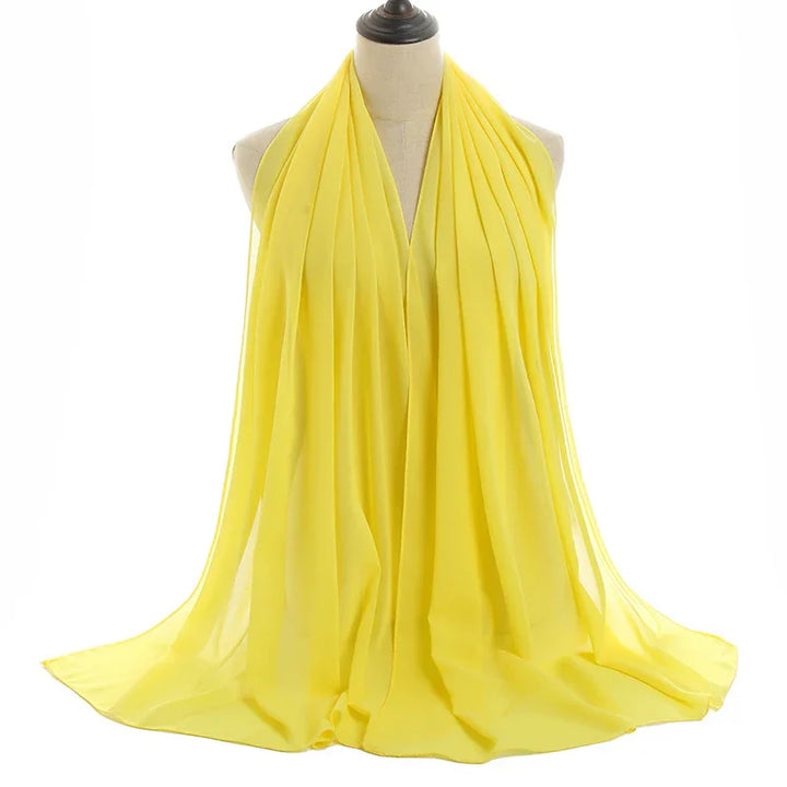 Lightweight yellow chiffon scarf draped on a mannequin against white background