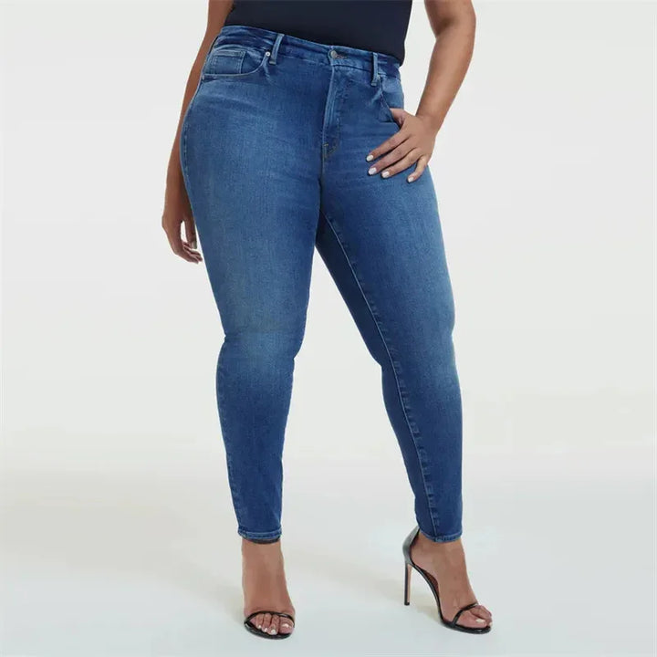 Woman wearing high-waisted blue skinny jeans and black strappy high heels on white background
