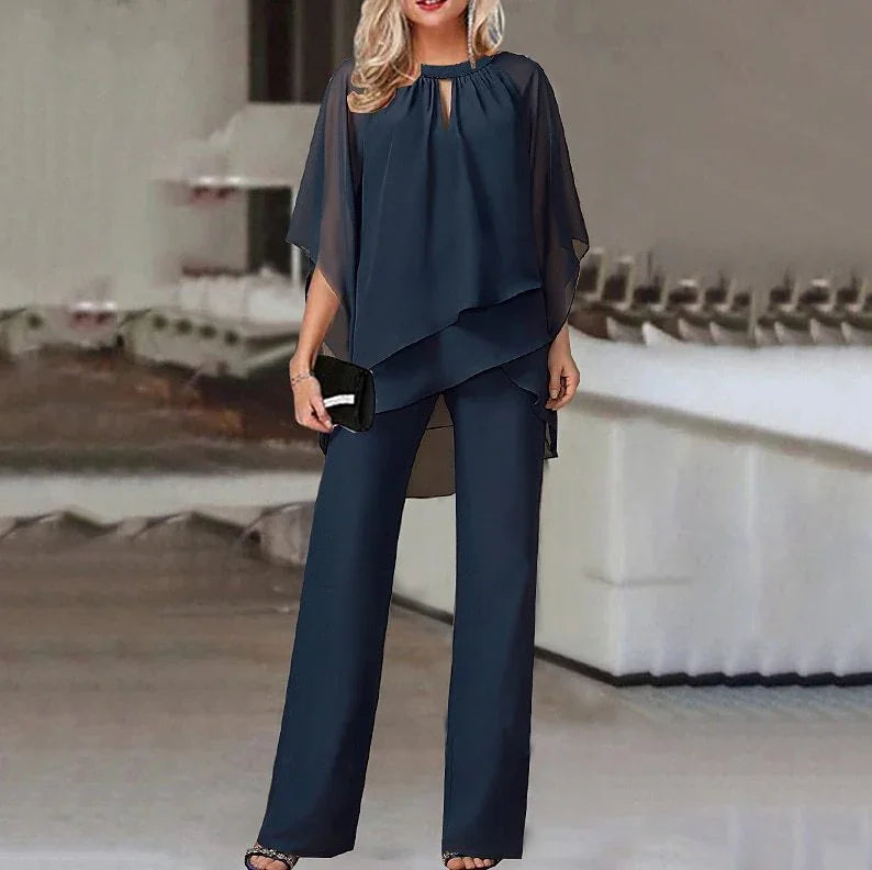 Woman wearing navy blue chiffon layered top and matching wide-leg pants outfit, holding black clutch