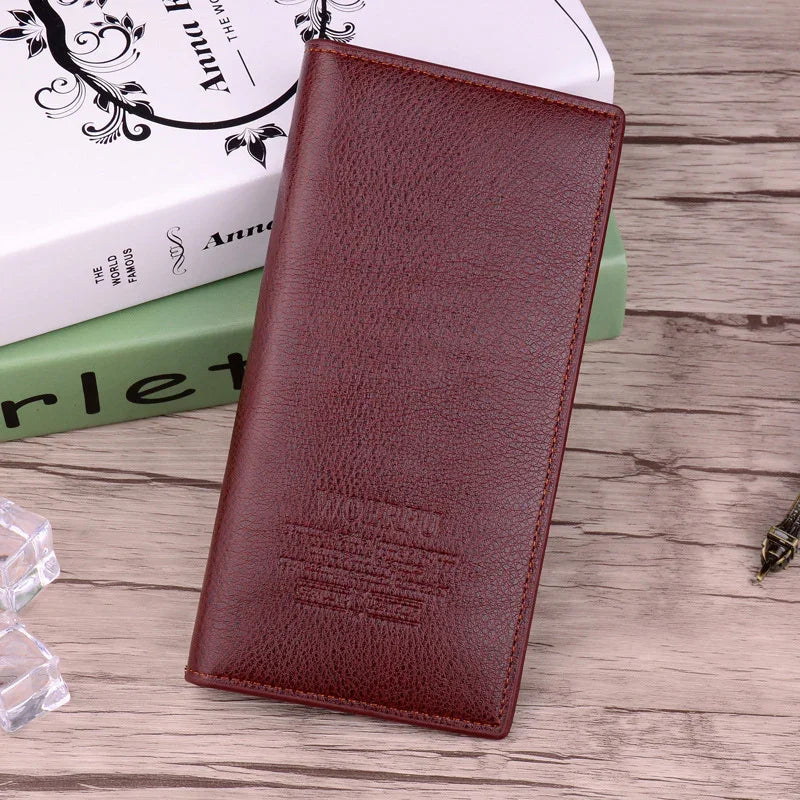 Brown leather long wallet on wooden table with books and decorative items