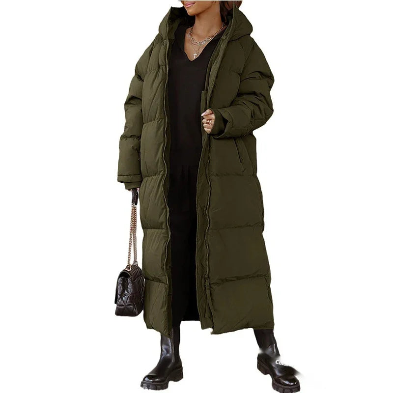 Woman wearing long olive green puffer coat with hood, black outfit, black boots, and black handbag