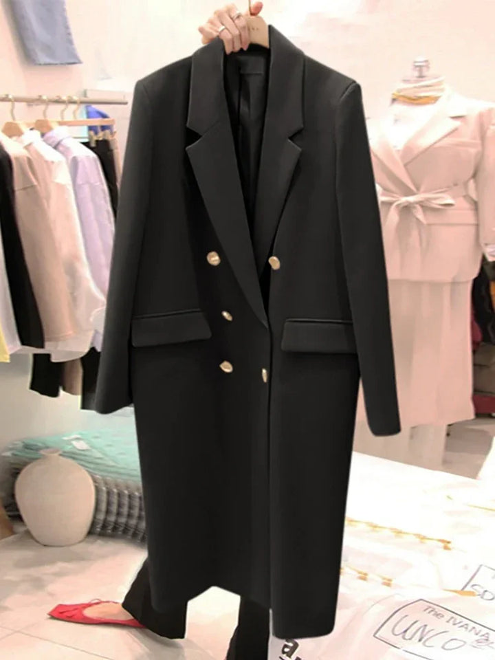 Black double-breasted long coat with gold buttons, displayed in a boutique setting