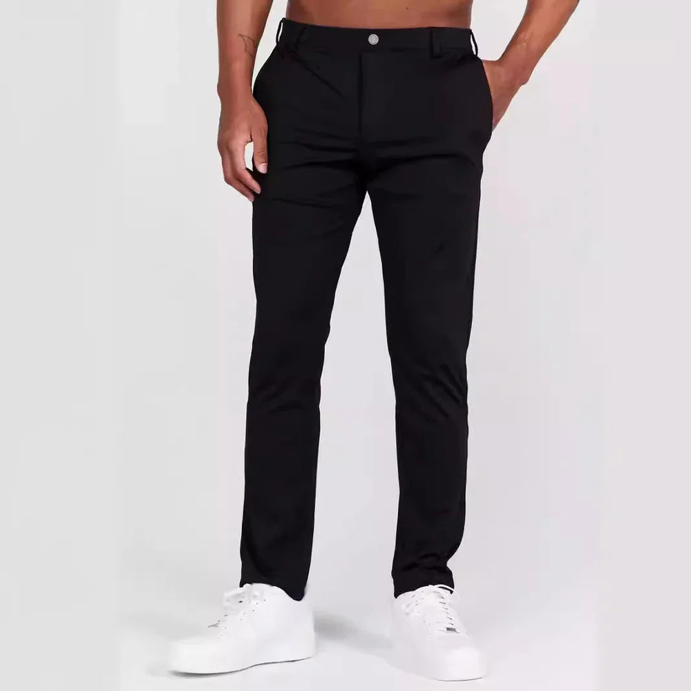 Male model wearing slim fit black pants and white sneakers on plain background