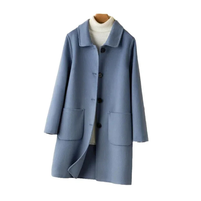 Light blue wool coat with black buttons and two front pockets over a white turtleneck sweater