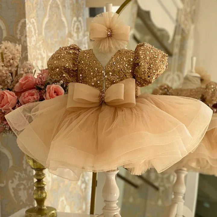 Elegant gold sequin toddler dress with puff sleeves and tulle skirt on mannequin