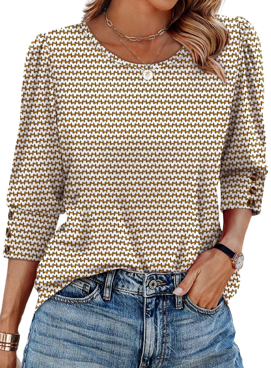 Woman wearing white and brown houndstooth patterned blouse with puff sleeves and blue denim jeans