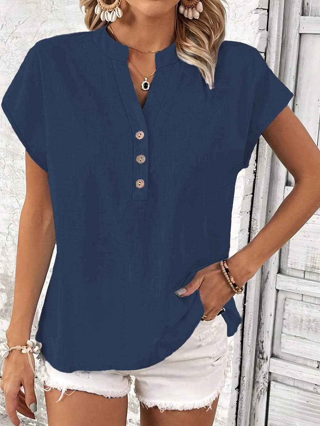 Woman wearing navy blue short sleeve henley shirt with buttons and white distressed shorts