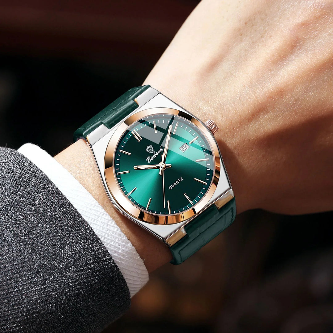 Men's wristwatch with green dial, gold bezel, and green leather strap worn with dark suit