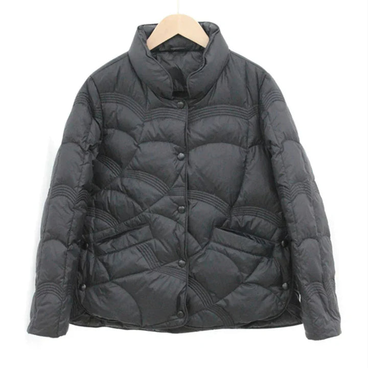 Black quilted puffer jacket with wave pattern, snap button front, and two pockets on wooden hanger