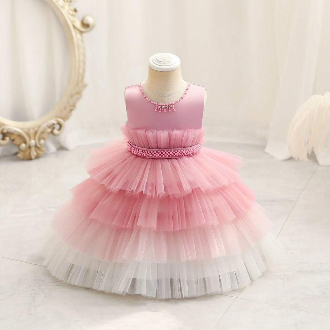 Elegant pink and white tiered tulle baby girl dress on mannequin with pearl details