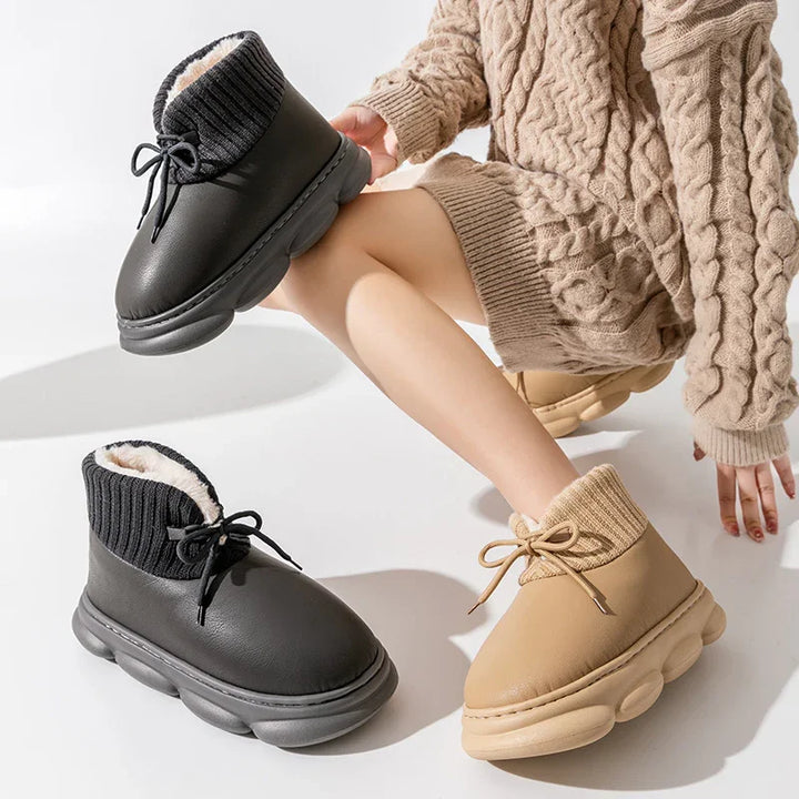Cozy winter boots with knitted cuffs in black and beige worn with a beige cable knit sweater dress