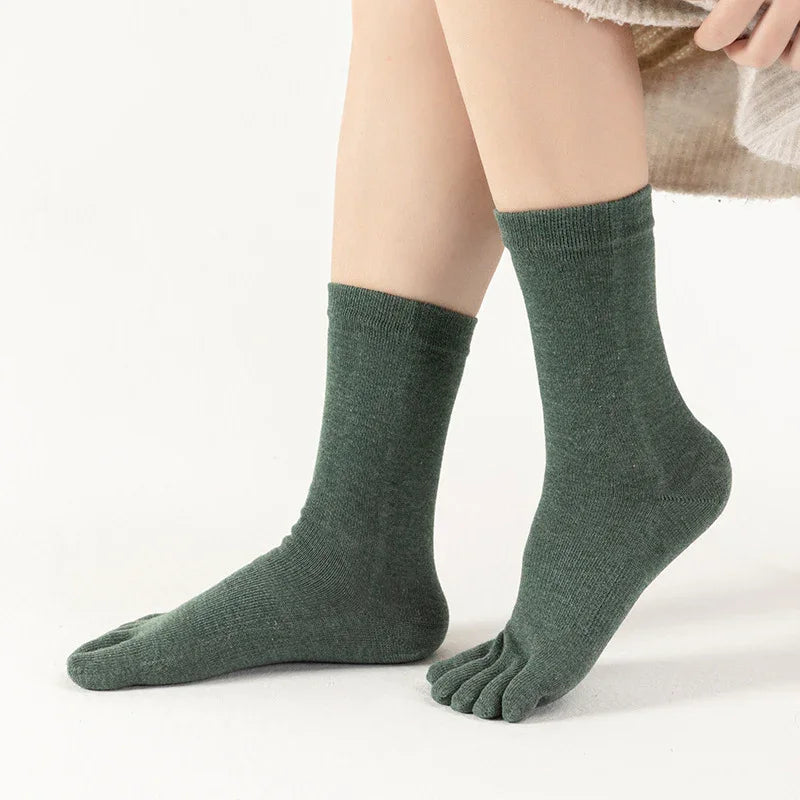 Person wearing green toe socks with a knit texture on a white background