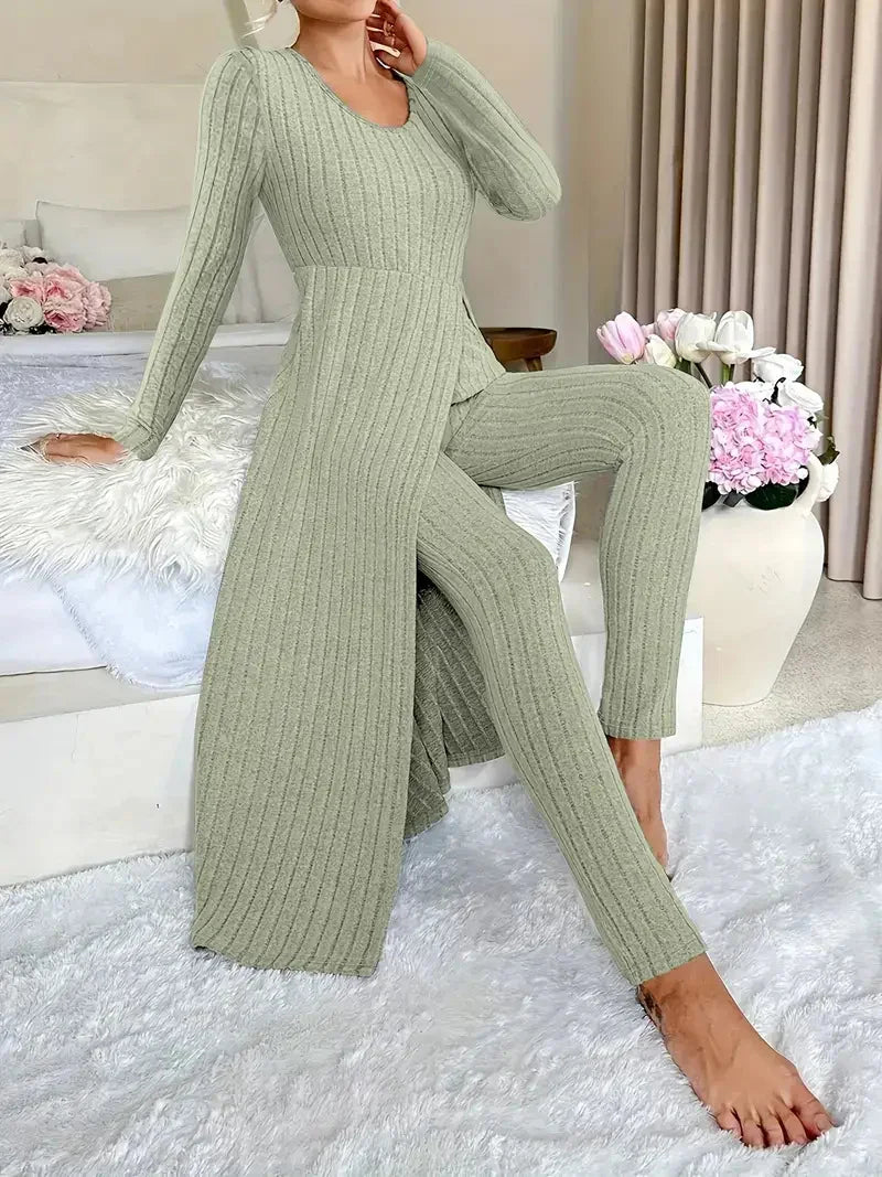 Woman wearing sage green ribbed knit long cardigan and matching pants, sitting on white fur rug indoors