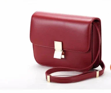 Elegant red leather crossbody bag with gold clasp and adjustable strap on white background