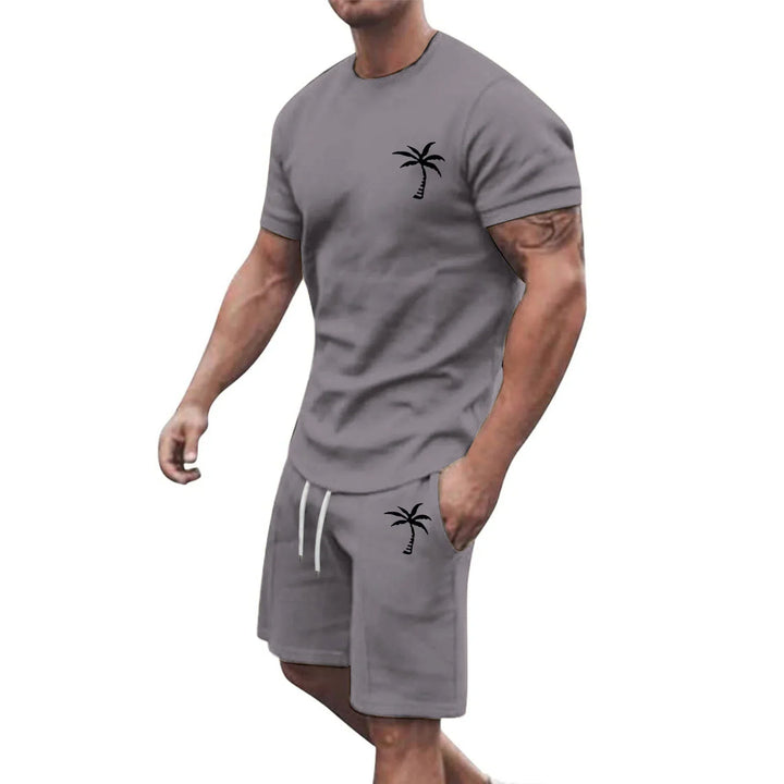 Muscular man wearing gray casual t-shirt and shorts set with black palm tree print, white drawstring