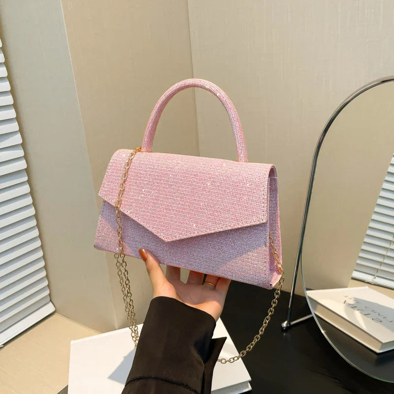 Hand holding a pink textured handbag with gold chain strap in a modern room