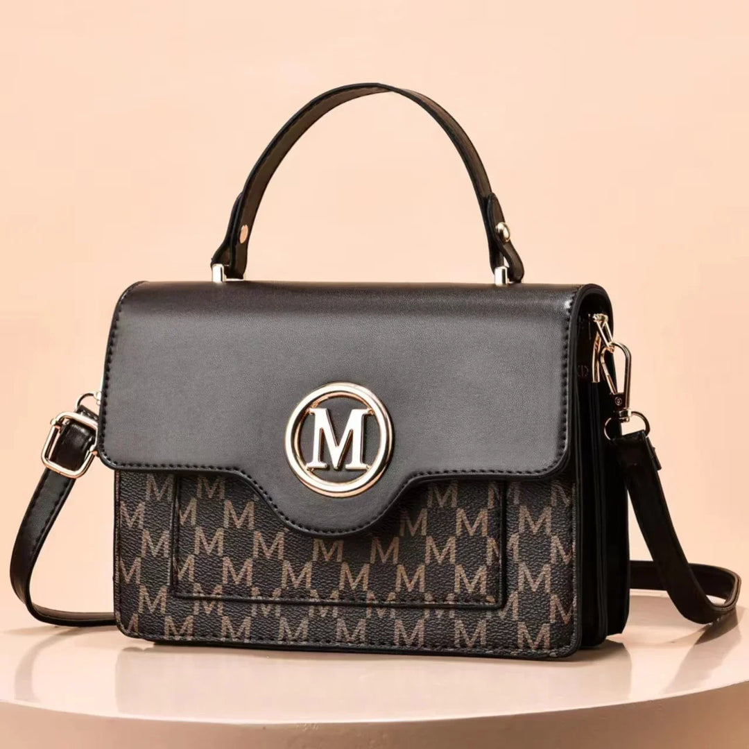 Black and brown designer handbag with embossed 'M' pattern and gold 'M' logo on front flap