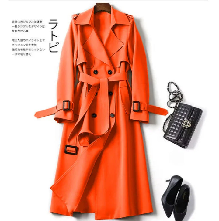 Bright orange double-breasted trench coat with belt, black quilted handbag, and black high heels on white background