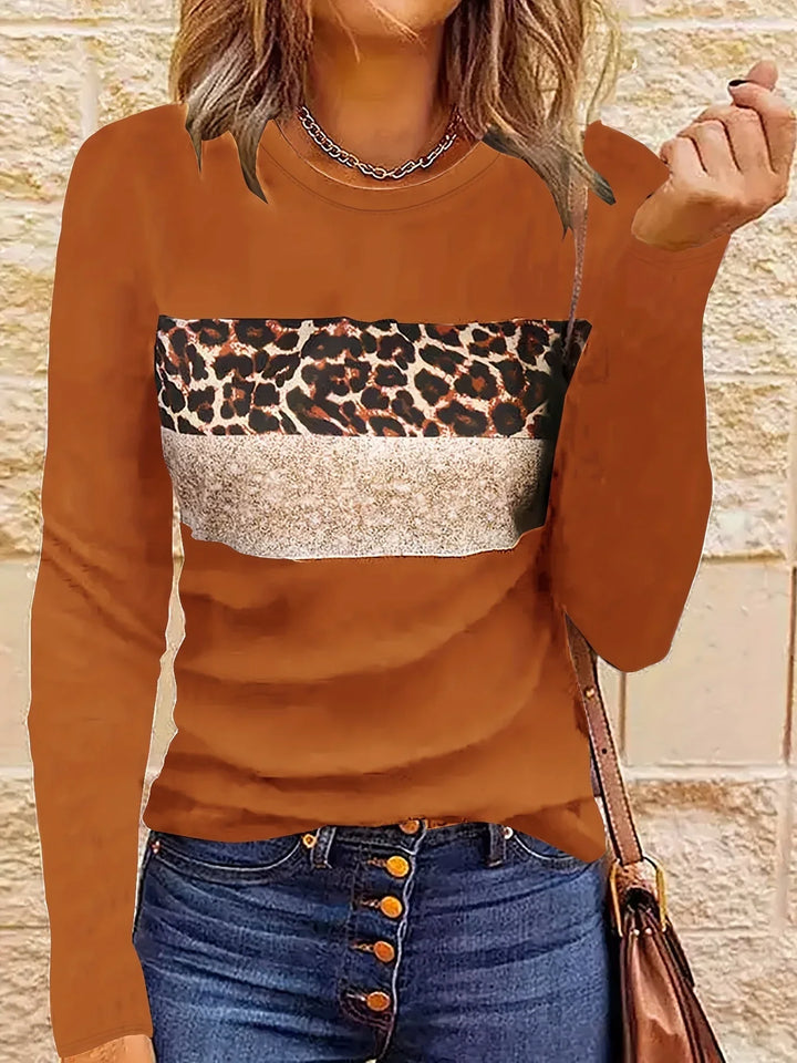 Woman wearing brown long-sleeve top with leopard and beige print, paired with blue button-up jeans