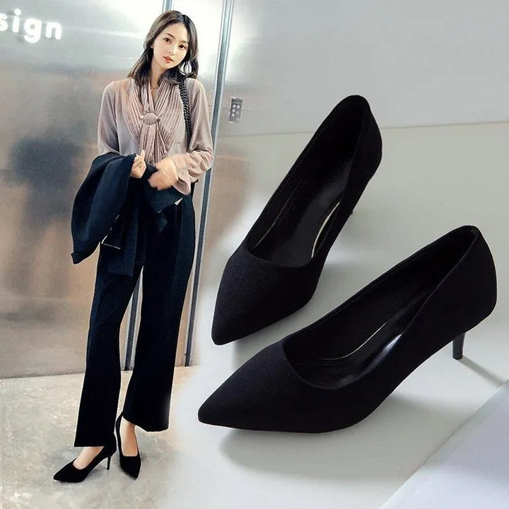 Woman wearing stylish black pointed-toe heels and black wide-leg pants, paired with a beige blouse