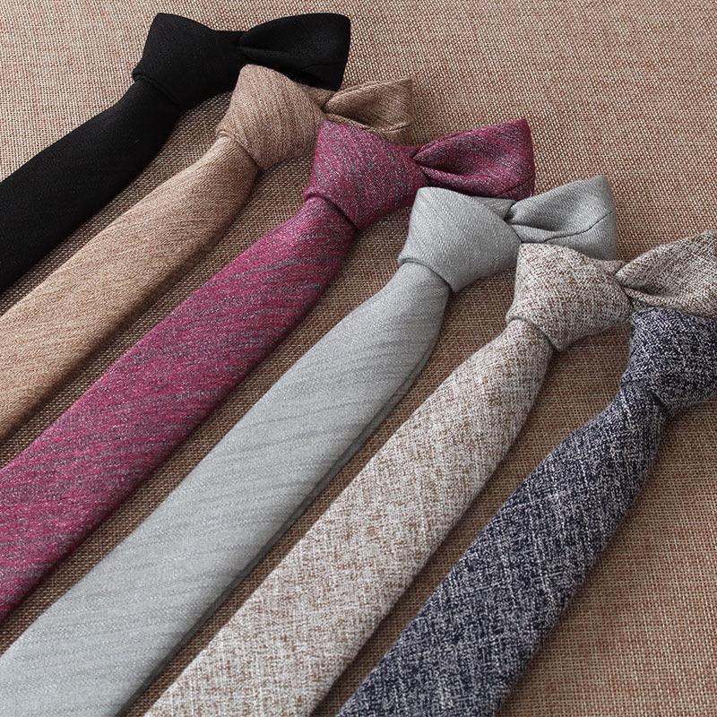 Six wool fabric neckties in black, beige, burgundy, light gray, tan, and navy blue laid on a textured brown surface