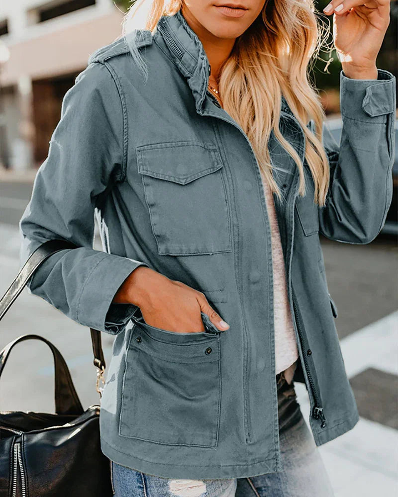 Woman wearing a blue utility jacket with front pockets, casual outfit, carrying a black handbag outdoors