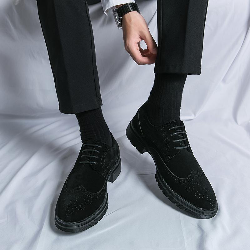 Man wearing black dress shoes and black socks with black trousers on white fabric background