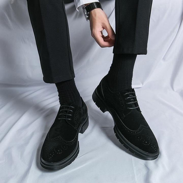 Man wearing black dress shoes and black socks with black trousers on white fabric background